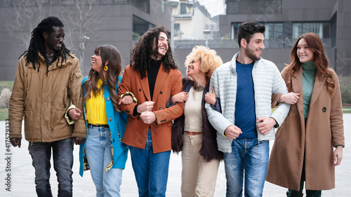 group of multiethinc couples walking and chatting, six friends smiling and laughing, concepts of inclusion, diversity and aggregation of the millennials generation