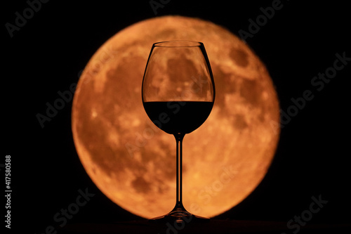 glass of wine at sunset with the moon in the background