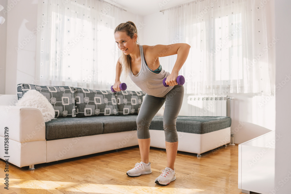 Muscular woman in good shape bending forward and fitness exercises with dumbbells. She is doing exercises for backs. Muscular woman in good shape bending forward and fitness exercises with dumbbells. She is doing exercises for backs.