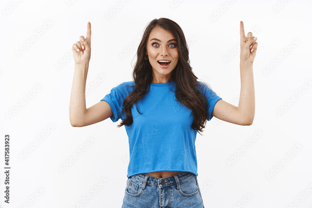 Excited and astounded young charming brunette pointing fingers up amused, gasping wondered, checking out something awesome, cool advertisement, standing white background rejoicing Excited and astounded young charming brunette pointing fingers up amused, gasping wondered, checking out something awesome, cool advertisement, standing white background rejoicing
