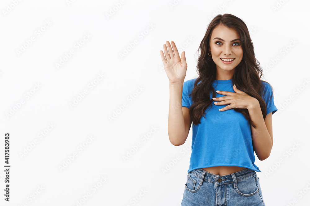 Hello my name is. Friendly charming brunette girl in blue t-shirt meating team members, join new group to study language course, raise arm in hi, informal greeting, white background Hello my name is. Friendly charming brunette girl in blue t-shirt meating team members, join new group to study language course, raise arm in hi, informal greeting, white background