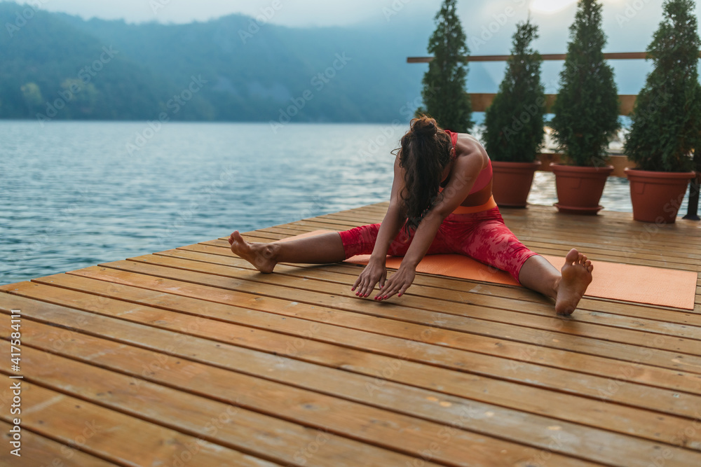 An attractive young woman doing a yoga near lake early in the morning