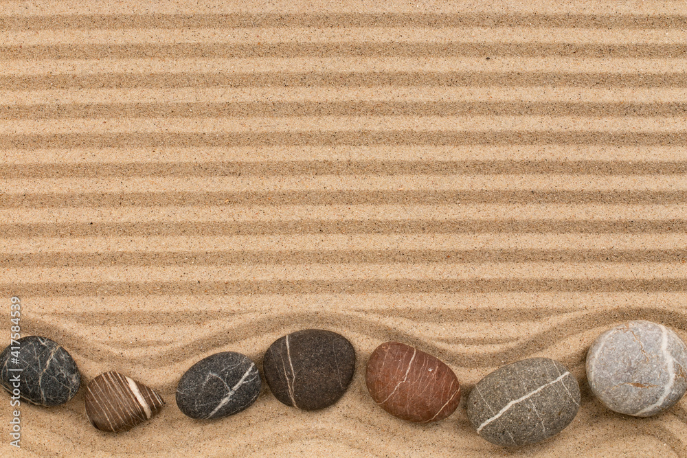 Zigzag made of striped stones, lying on striped sand.