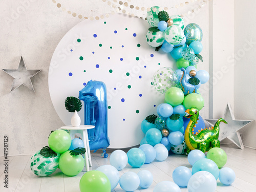 Birthday decorations - gifts, toys, balloons, garland and number for little baby party on a white wall background.