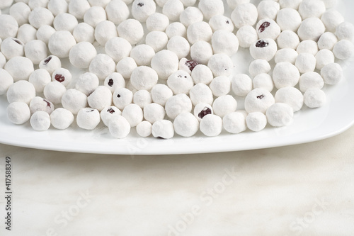 Cranberries in powdered sugar on a white plate. Copy space.