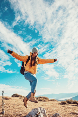 Cheering woman backpacker enjoy the view on sunrise mountain top cliff edge