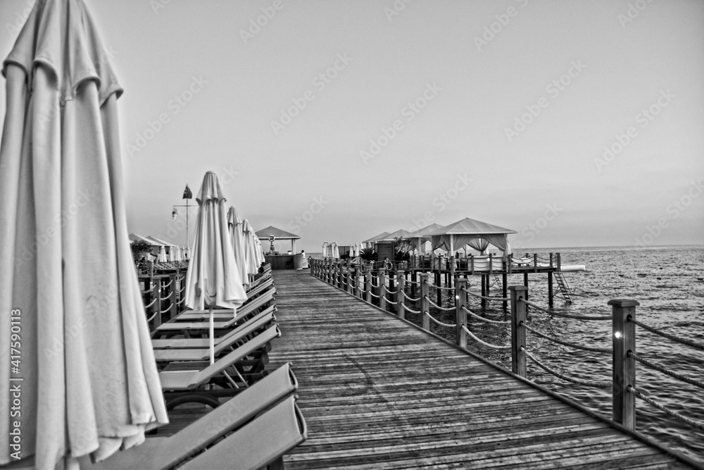  holiday landscape by the sea during sunset with sun loungers and umbrellas on the pier