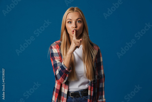 Serious beautiful blonde girl showing silence gesture