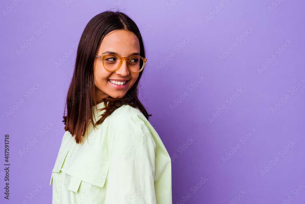 Young mixed race woman isolated looks aside smiling, cheerful and pleasant.