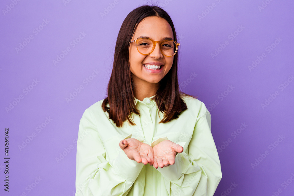 Young mixed race woman isolated holding something with palms, offering to camera. Young mixed race woman isolated holding something with palms, offering to camera.