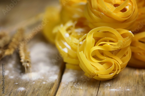 Raw fettuccine pasta. Spikelets and flour. The concept of cooking pasta nest.