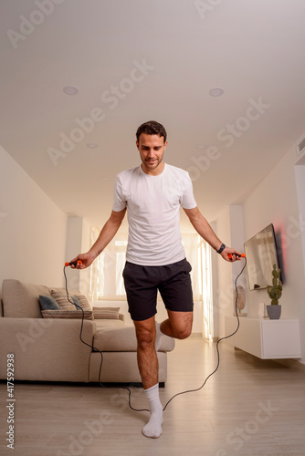 man doing exercises at home with jump rope