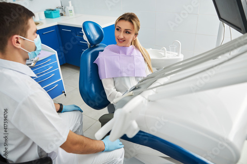 Dentist is sitting near his female patient