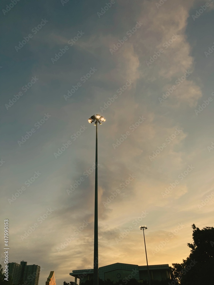 Illuminated street light lamp post against blue sky background