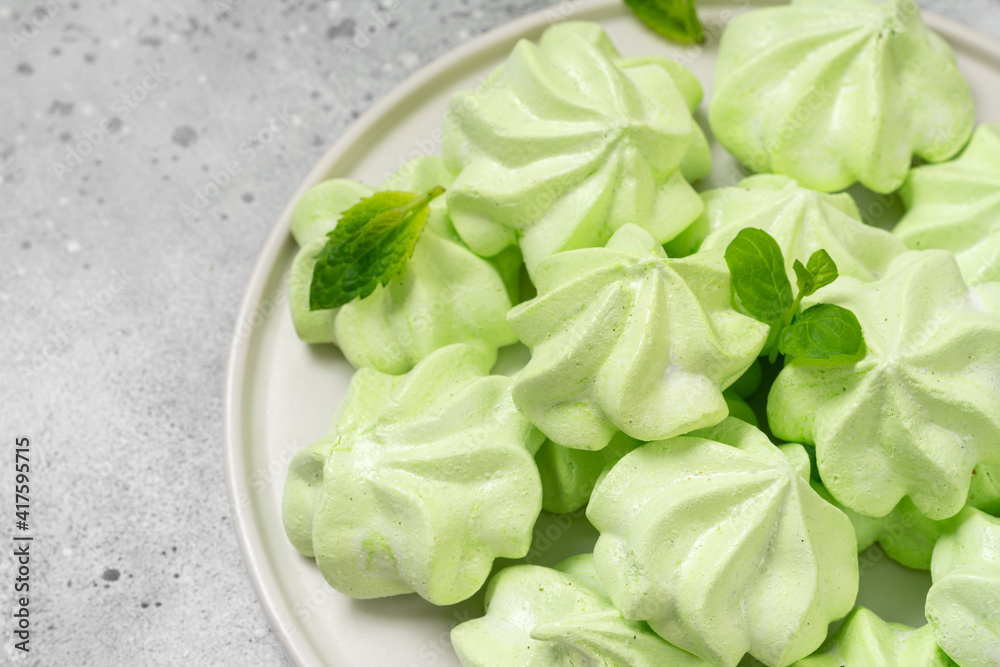 Mint or fruit meringue in a white plate on a light gray kitchen table. French or Italian protein dessert Mint or fruit meringue in a white plate on a light gray kitchen table. French or Italian protein dessert