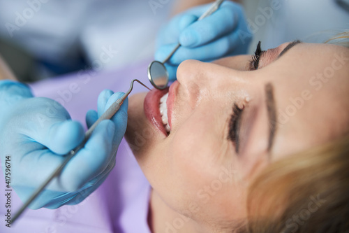 Dental specialist examining teeth with stomatological instruments