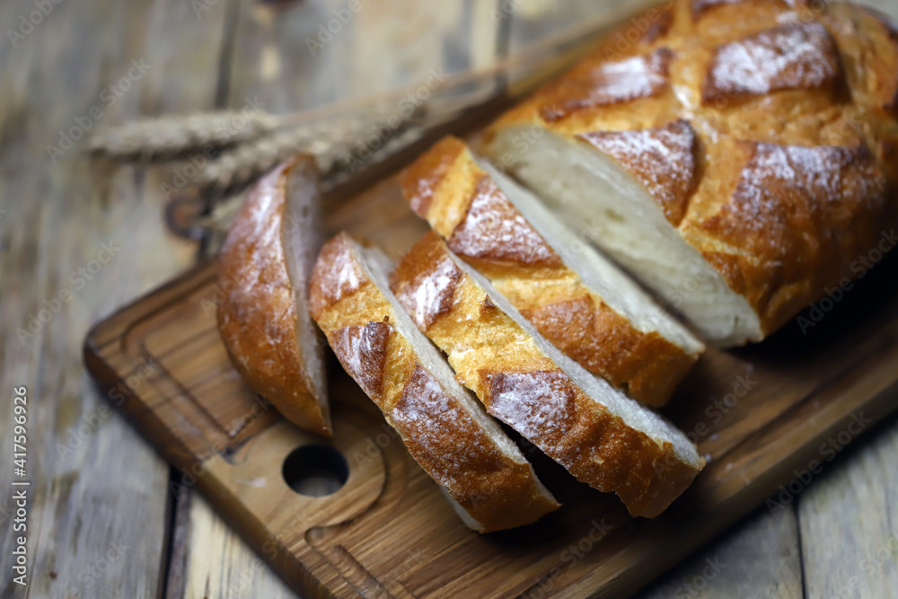 Fresh wheat bread slices on a wooden surface. Ears of wheat. Rustic style. Fresh wheat bread slices on a wooden surface. Ears of wheat. Rustic style.