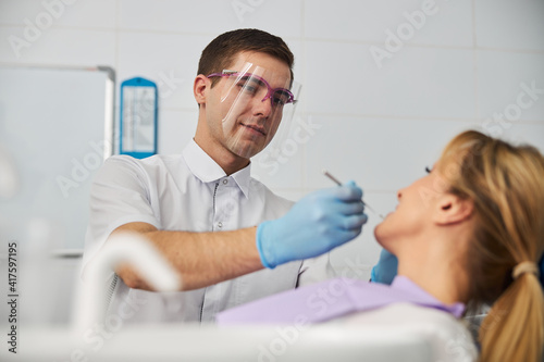 Collected dental professional using mouth mirror on lady