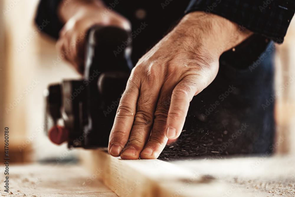 Carpenter's hands working with electric planer in a workshop Carpenter's hands working with electric planer in a workshop