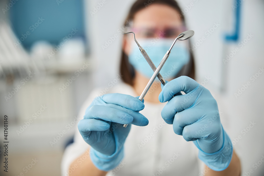 Dental mirror and probe getting crossed by dentist Dental mirror and probe getting crossed by dentist