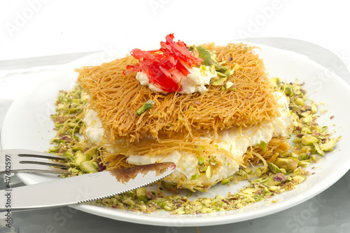 Turkish dessert kunefe, kunafa, kadayif with pistachio powder and cheese, served hot, very sweet. Turkish traditional dessert.Lebanese dessert of Kunafa isolated on white.