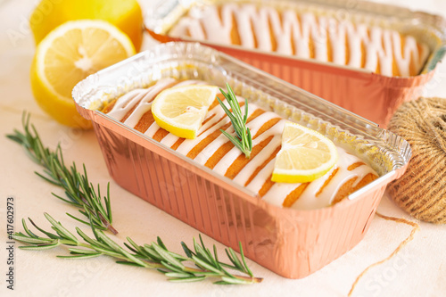 Lemon butter cake or pound cake top with lemon icing glaze decorated with lemon sliced and rosemary leaves in aluminum foil loaf on table. Delicious taste with sweet and sour. Homemade bakery concept.