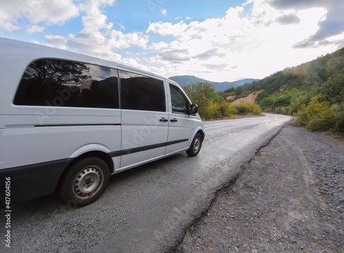 minivan moves along a winding mountain road.