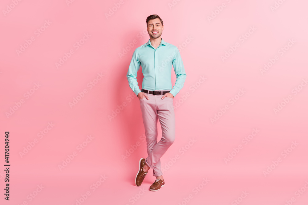 Full length body size photo of handsome man in formal wear smiling hands in pockets isolated on pastel pink color background Full length body size photo of handsome man in formal wear smiling hands in pockets isolated on pastel pink color background