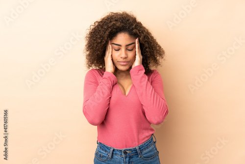 Young African American woman isolated on beige background with headache
