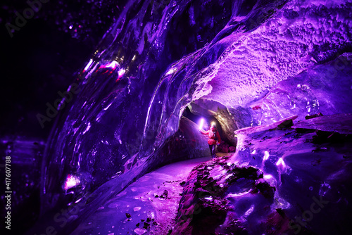 Valokuva Man with pink light exploring an amazing glacial ice cave