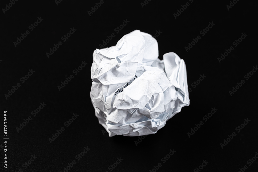 A crumpled paper ball in a black background