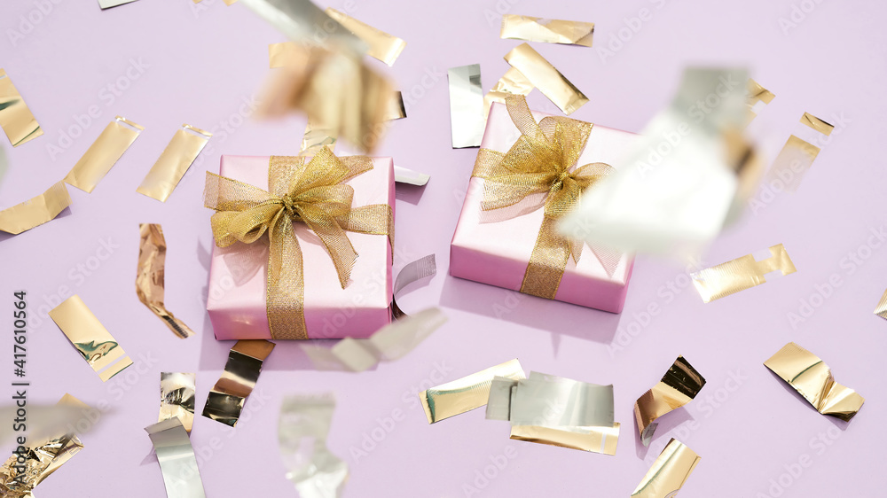 Happy womens day. Top view of two small wrapped gift boxes with golden bows on pastel pink background Happy womens day. Top view of two small wrapped gift boxes with golden bows on pastel pink background