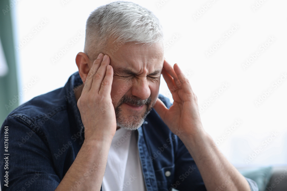 Closeup of mature grey-haired man suffering from headache Closeup of mature grey-haired man suffering from headache