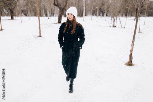 Outdoor portrait. Young beautiful happy smiling girl walking on street. Model looking aside, wearing stylish coat, hat. City lifestyle.