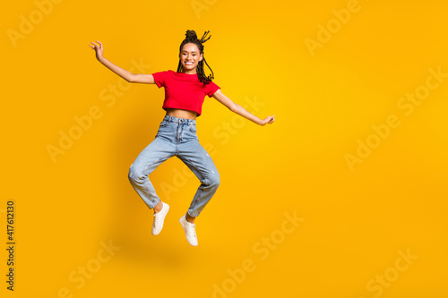 Full size photo of attractive carefree dark skin person jumping beaming smile isolated on yellow color background