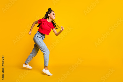 Full length body size profile side view of strong active cheerful girl jumping running copy space isolated bright yellow color background