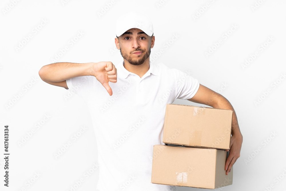 Delivery Arabian man isolated on blue background showing thumb down sign Delivery Arabian man isolated on blue background showing thumb down sign
