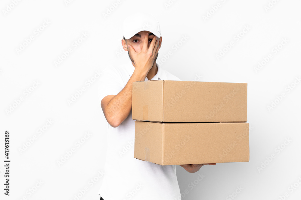 Delivery Arabian man isolated on blue background covering eyes and looking through fingers Delivery Arabian man isolated on blue background covering eyes and looking through fingers