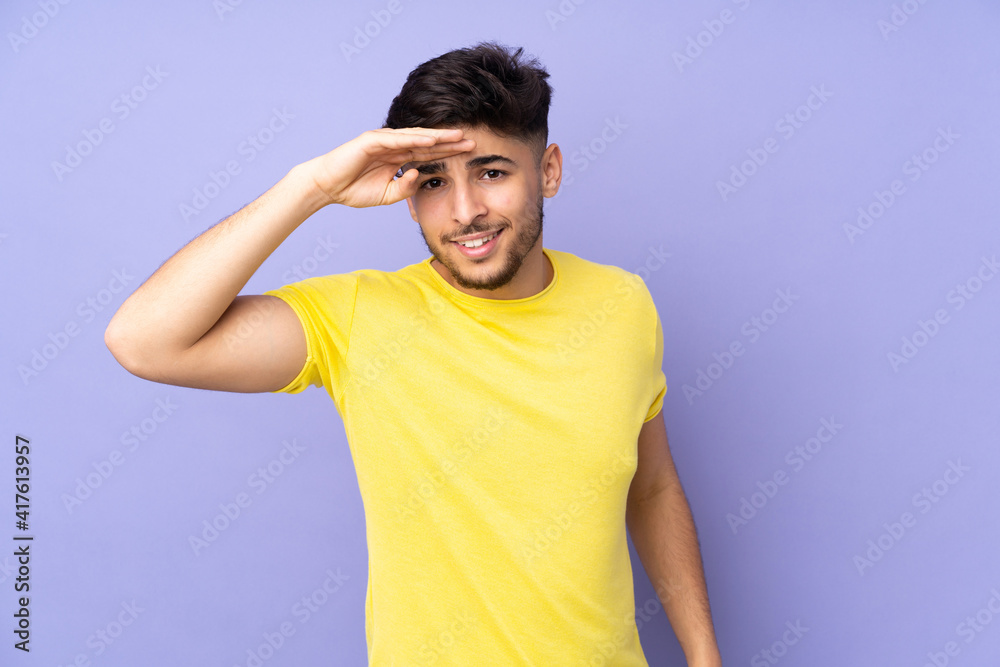 Arabian handsome man over isolated background looking far away with hand to look something Arabian handsome man over isolated background looking far away with hand to look something