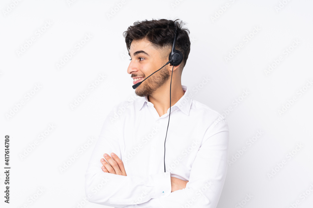 Telemarketer Arabian man working with a headset isolated on white background looking to the side Telemarketer Arabian man working with a headset isolated on white background looking to the side