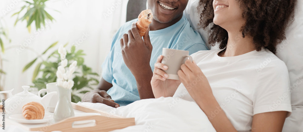 Φωτογραφία Young beautiful loving african american couple sits in bed, man and woman holds