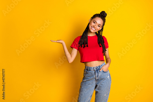 Portrait of pretty cheerful girl holding on palm copy space ad presentation isolated over bright yellow color background