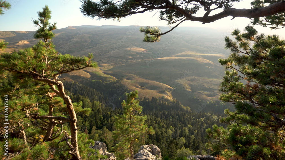 View from the cliff to high hills and forests through the trees.