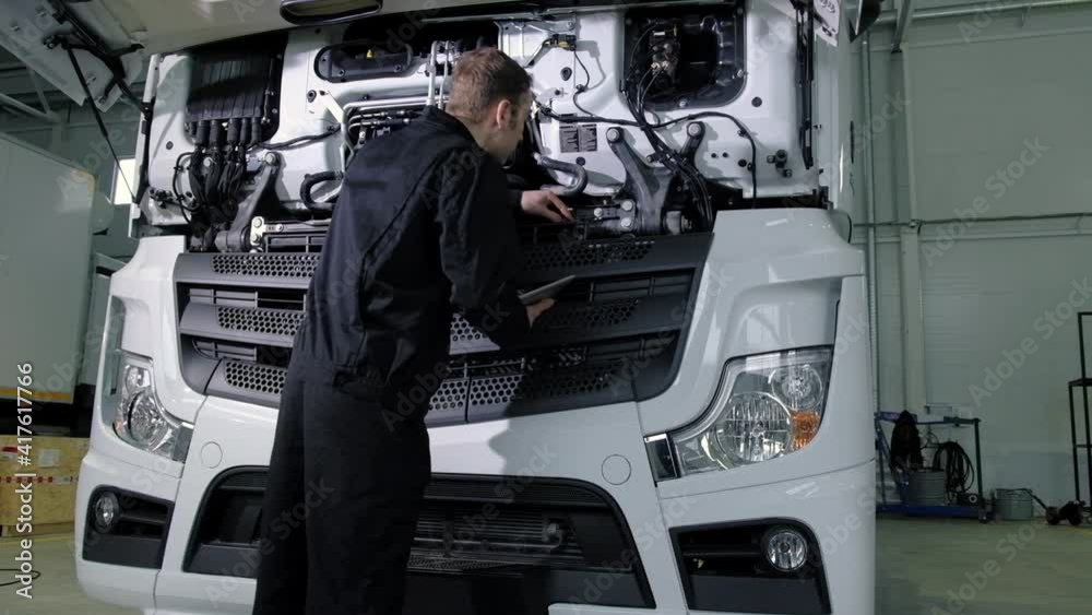 Repair diagnostics and maintenance of cars in service center. mechanic engineer of car service inspects transport cargo uses tablet to search for errors and breakdowns and writes data to the computer Repair diagnostics and maintenance of cars in service center. mechanic engineer of car service inspects transport cargo uses tablet to search for errors and breakdowns and writes data to the computer
