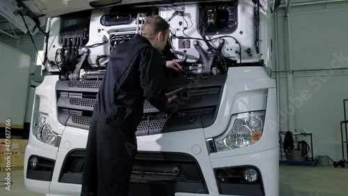 Repair diagnostics and maintenance of cars in service center. mechanic engineer of car service inspects transport cargo uses tablet to search for errors and breakdowns and writes data to the computer