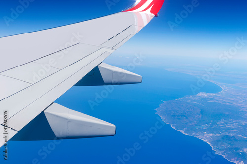 Airplane wing fly over sea and coast. Travel vacation concept.