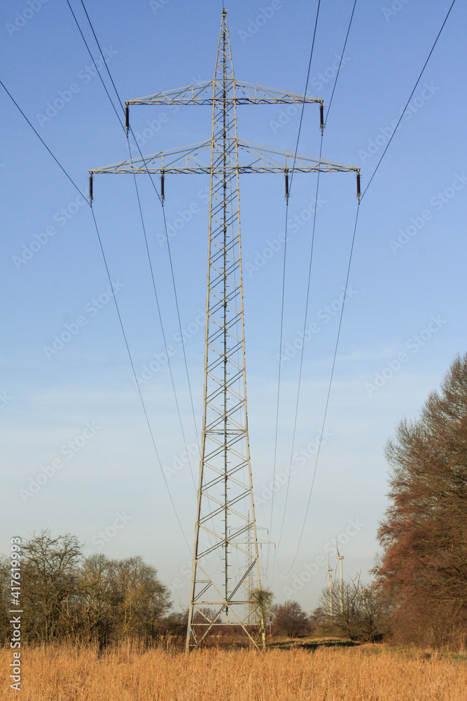 power line with windmill in the background crossing a field power line with windmill in the background crossing a field