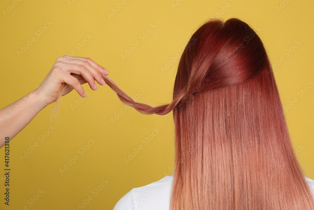 Fototapeta premium Woman with bright dyed hair on yellow background, back view