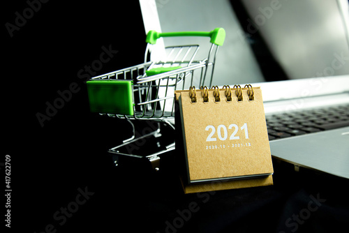 Calendar 2021 with Shopping cart and laptop with dark background. Business Shopping concept. Copy space. photo