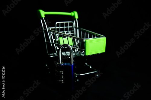 Low key Silver shopping cart with padlock on dark background. Shopping or e-commerce. security shopping concept.